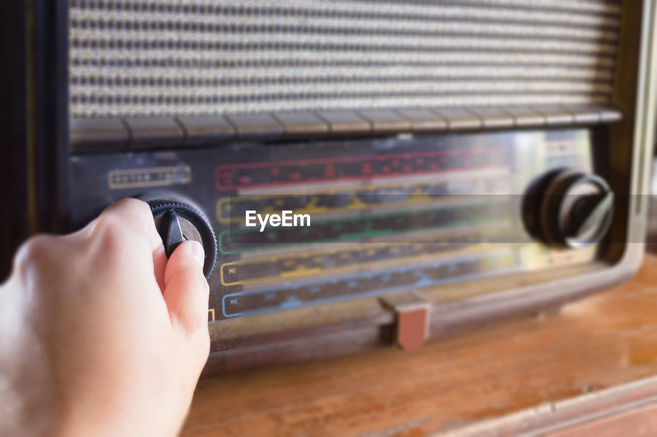 Cropped hand of woman playing radio at table