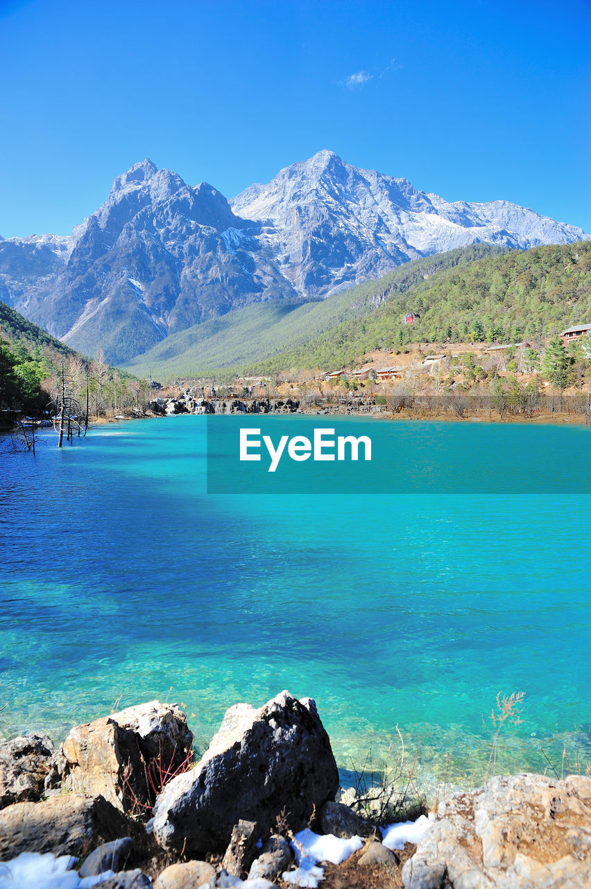 SCENIC VIEW OF SEA BY MOUNTAIN AGAINST BLUE SKY