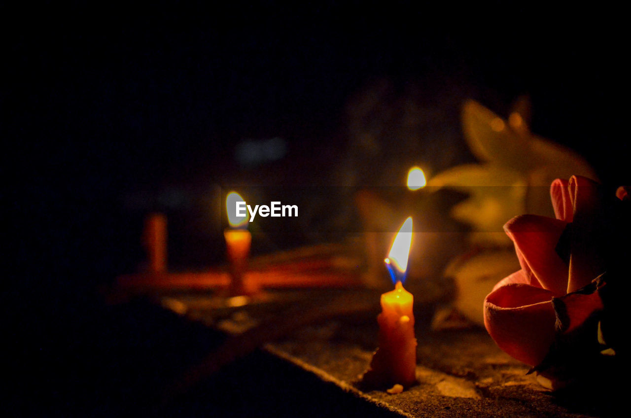 Close-up of lit candles burning in the dark