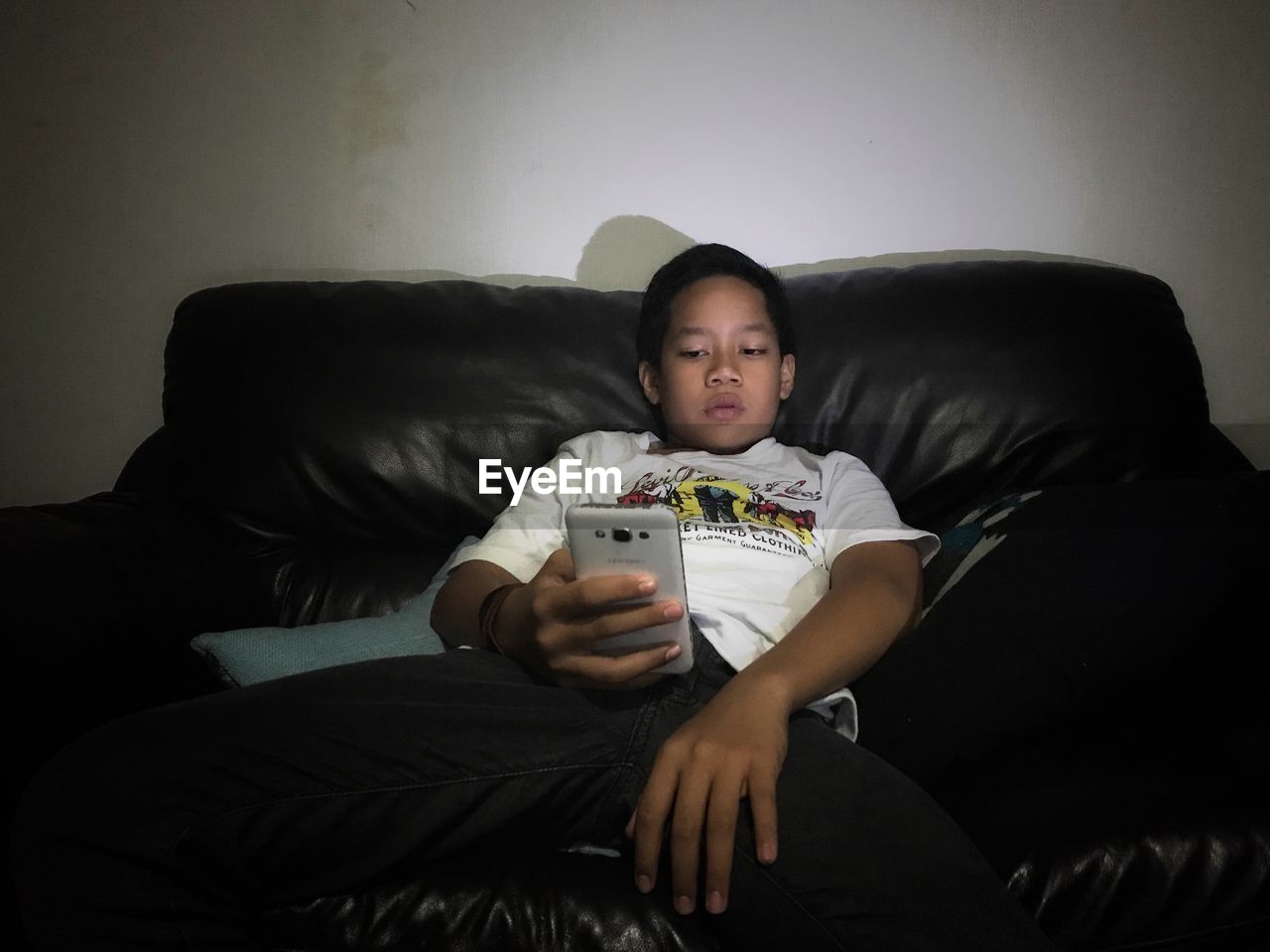 Boy using mobile phone while sitting on sofa at home