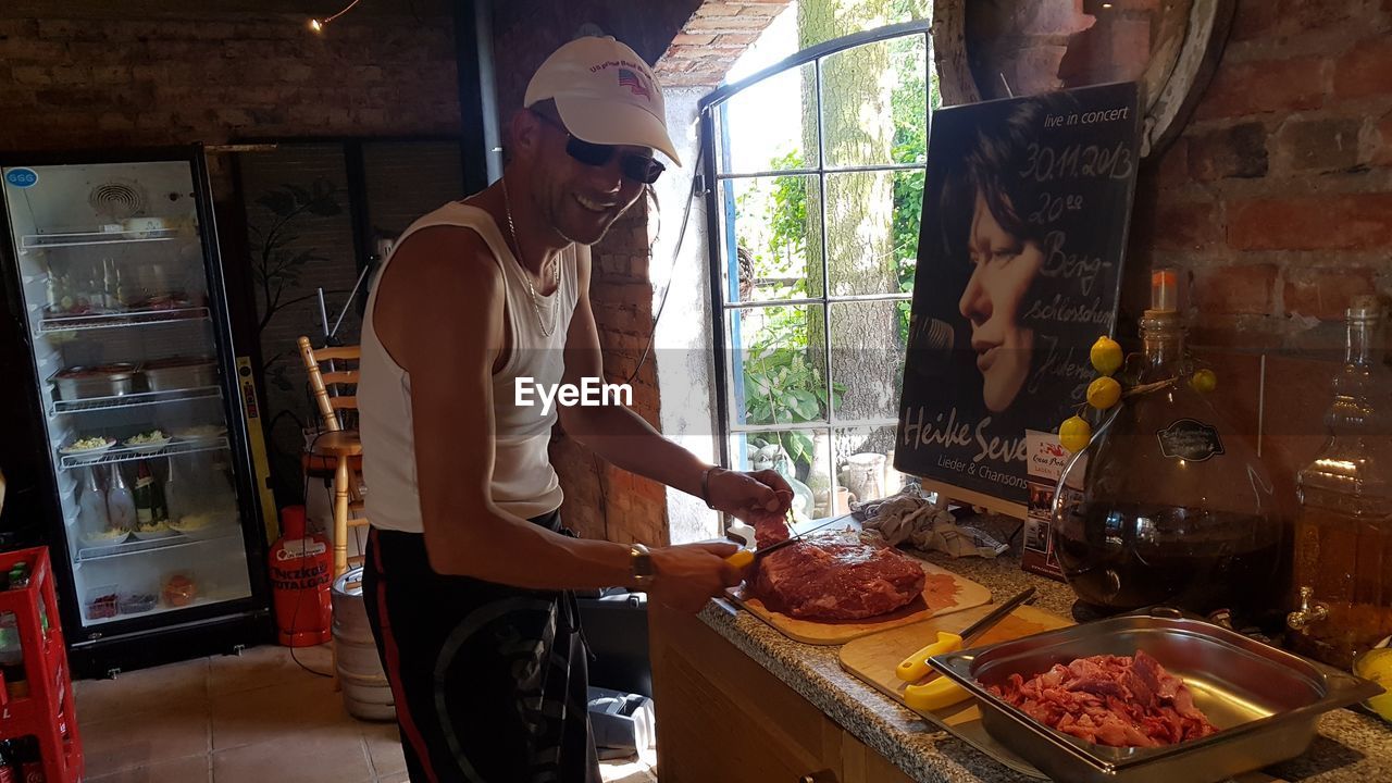 MIDSECTION OF MAN PREPARING FOOD AT KITCHEN