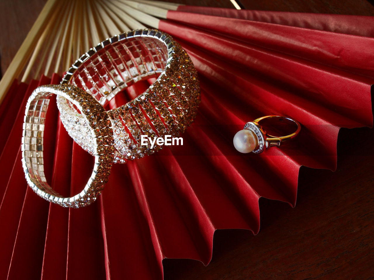 Close-up of jewelry on red hand fan at table