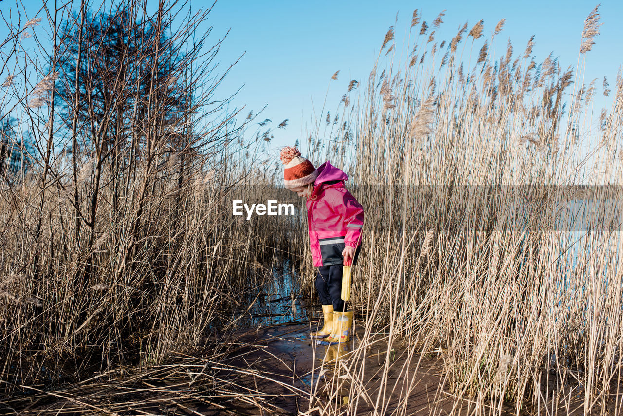 Young girl playing in long grass by the beach in winter