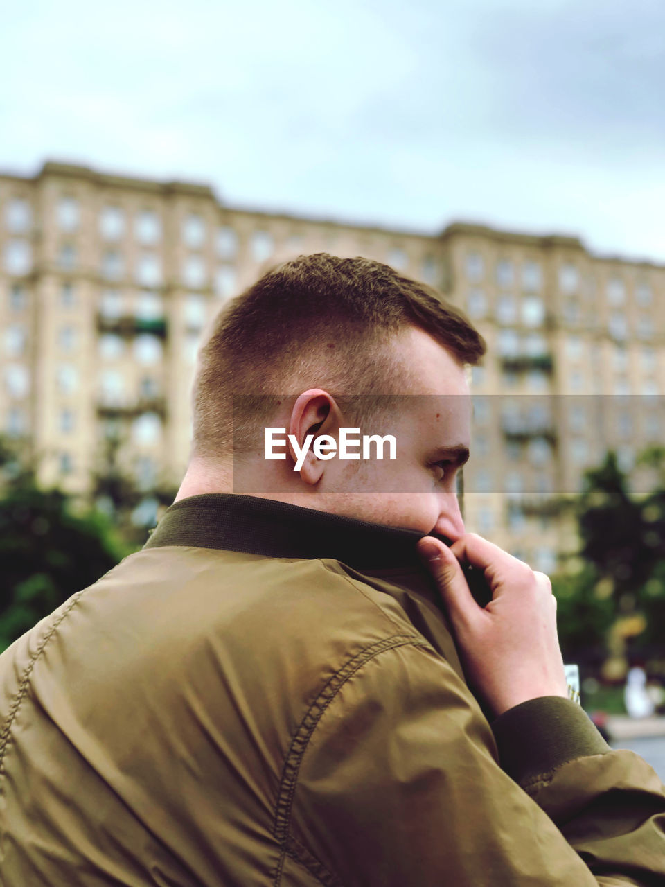 Close-up of young man wearing warm clothing against building