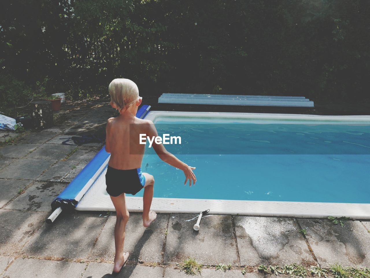 FULL LENGTH REAR VIEW OF BOY ON SWIMMING POOL