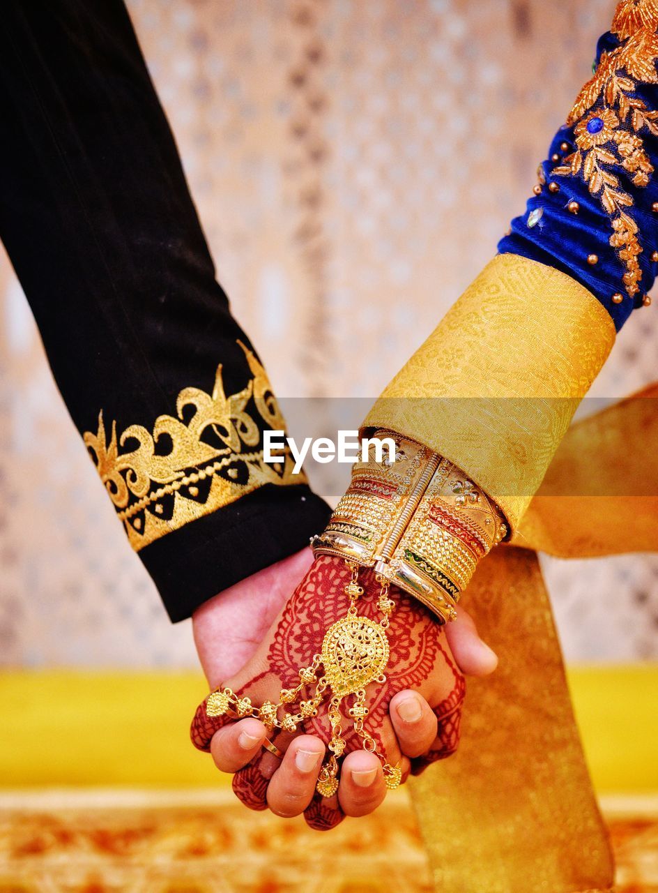 Midsection of couple holding hands during wedding ceremony