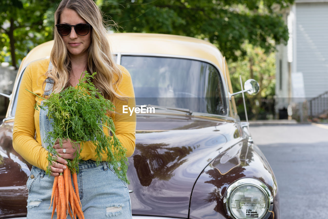 YOUNG WOMAN WEARING SUNGLASSES WHILE HOLDING CAR