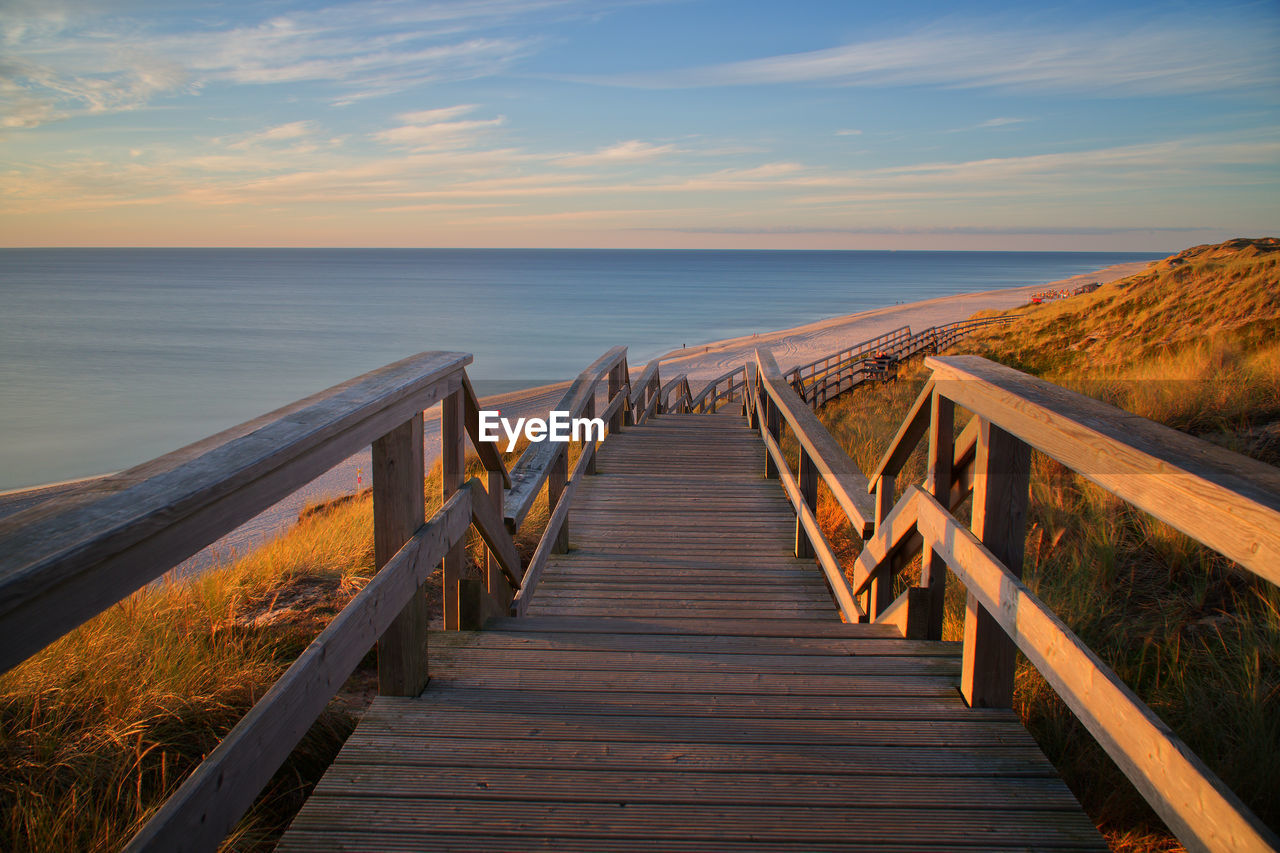 Pier over sea against sky during sunset