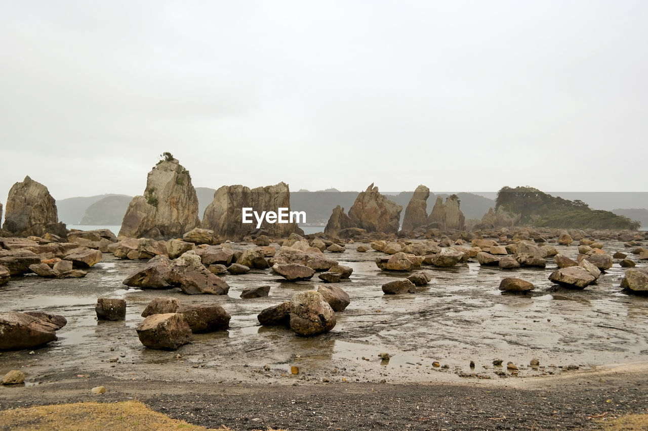 ROCK FORMATIONS ON BEACH AGAINST SKY