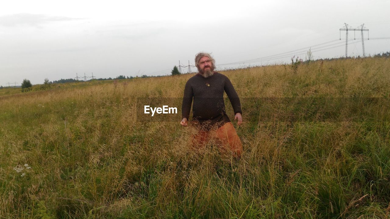 Man standing on grassy field against sky