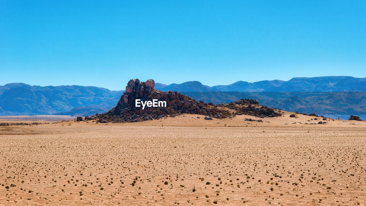 Scenic view of desert against clear blue sky