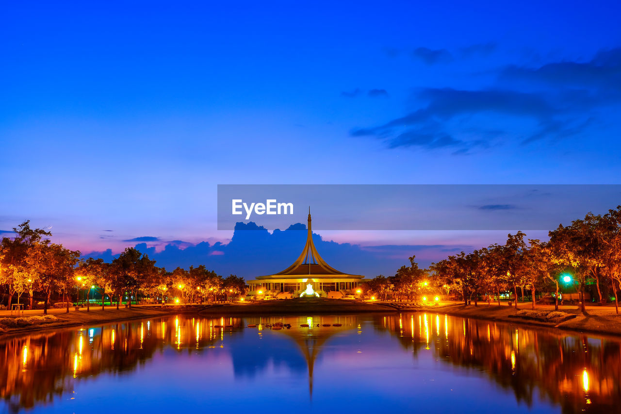 REFLECTION OF ILLUMINATED BUILDING IN LAKE AT DUSK