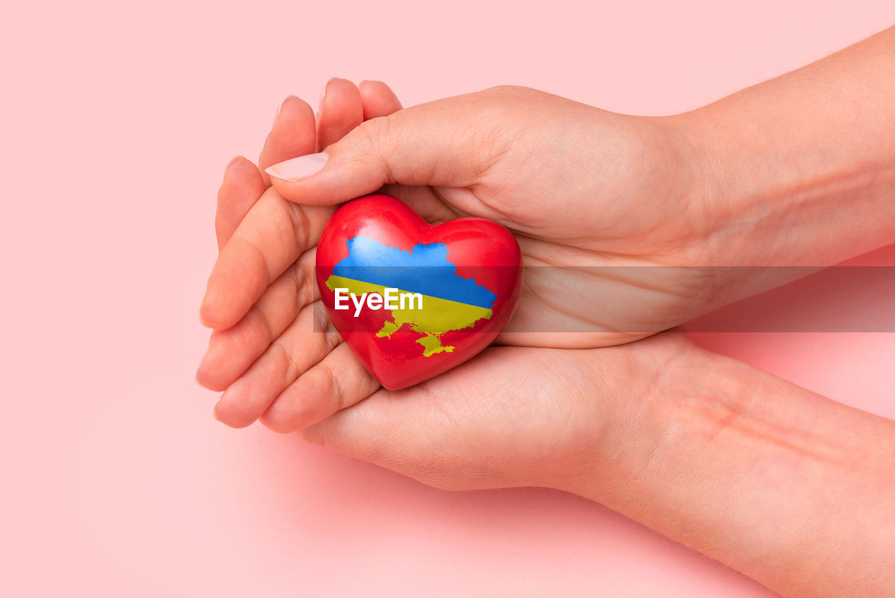 Hand holding a heart with ukrainian national colors