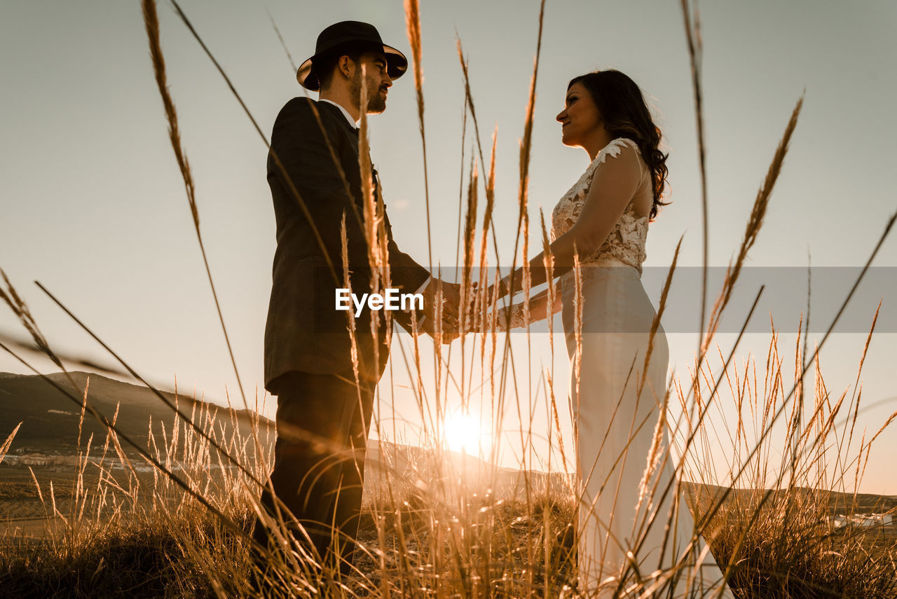 Couple in a field at sunset among dry plants. wedding concept