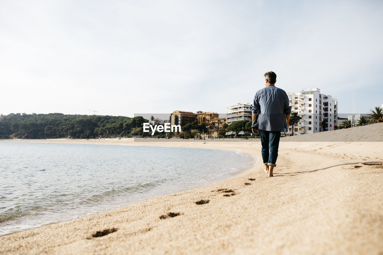 Man walking on beach during sunny day