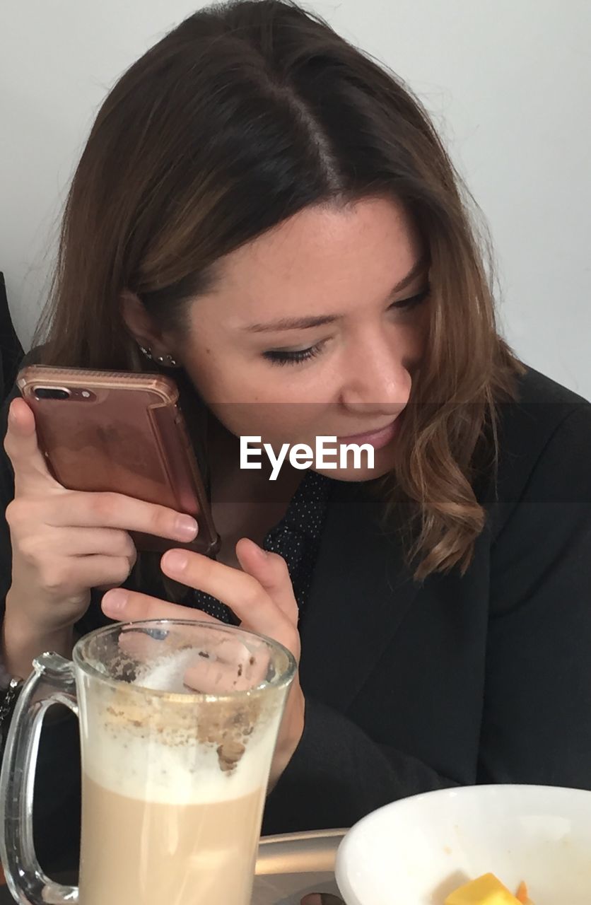 Close-up of young woman using phone in restaurant