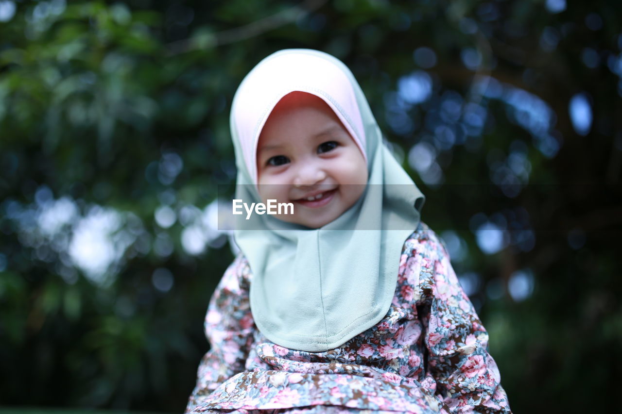 Portrait of smiling girl standing against tree