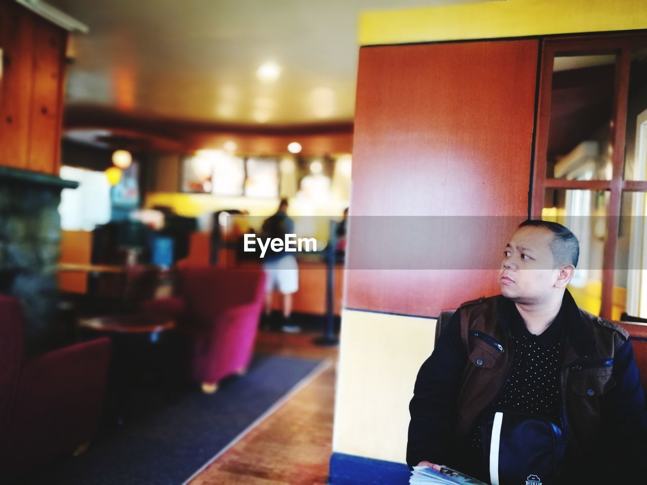 Young man looking away while sitting in restaurant