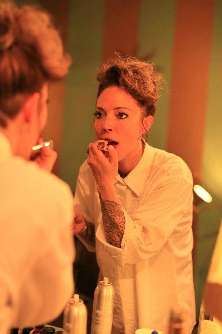 Woman applying lipstick while reflecting in mirror