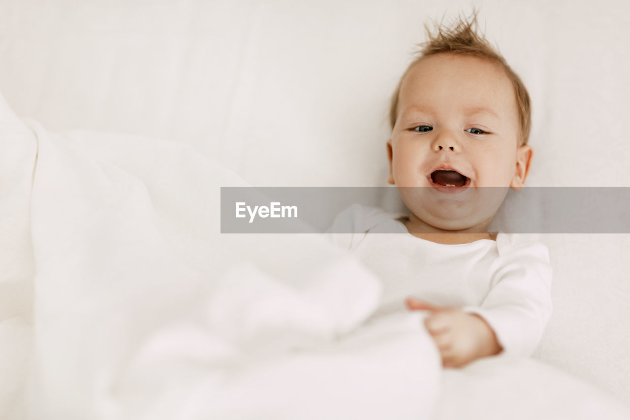 Portrait of cute baby girl on bed at home