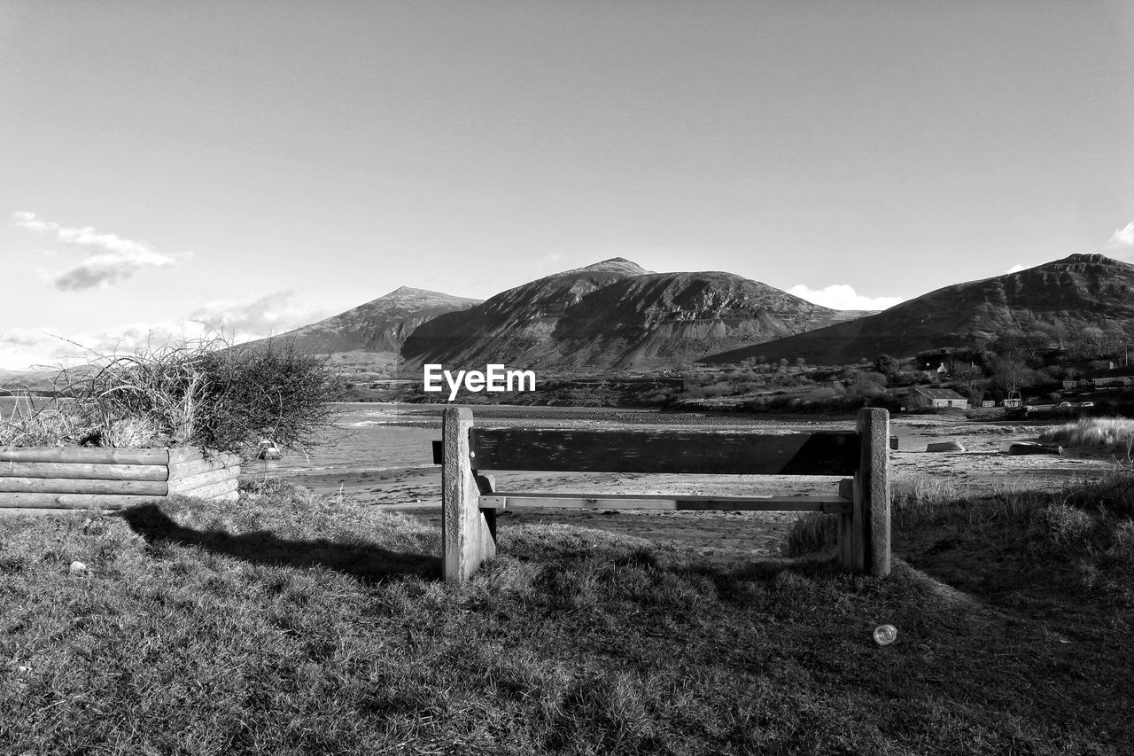 Scenic view of agricultural field against sky with bench