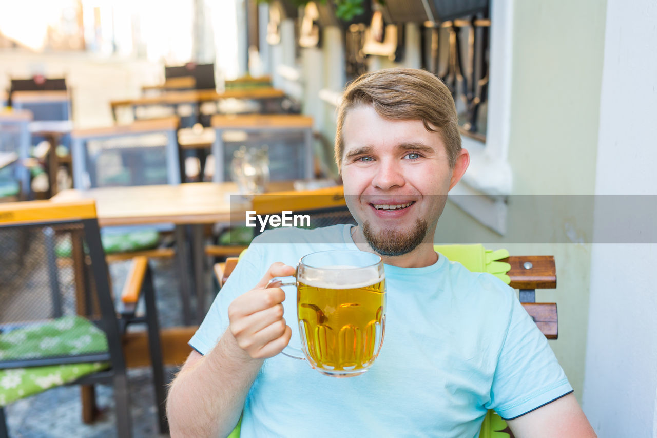 PORTRAIT OF YOUNG MAN DRINKING GLASSES