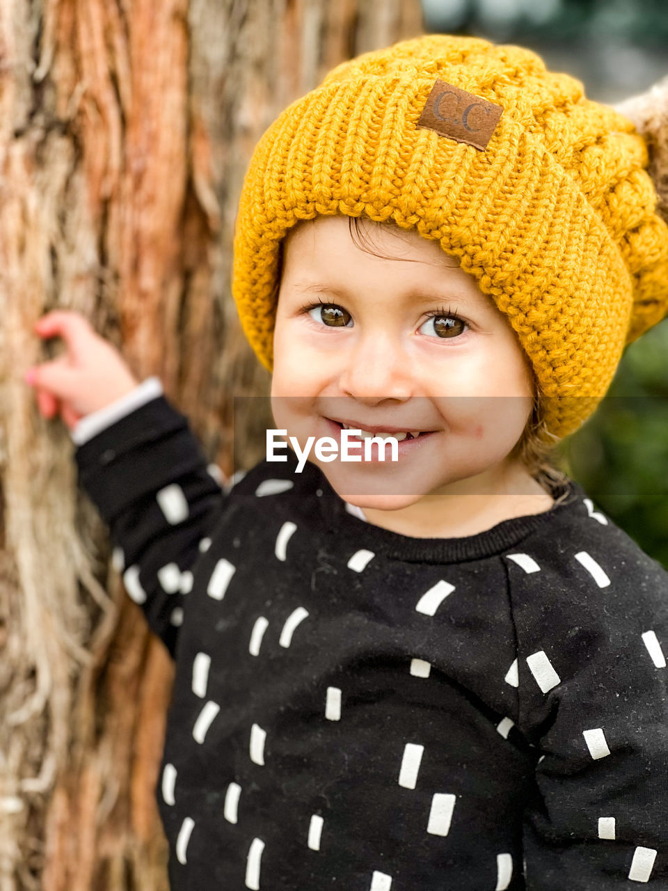 Portrait of smiling toddler with yellow beanie with puffy ears