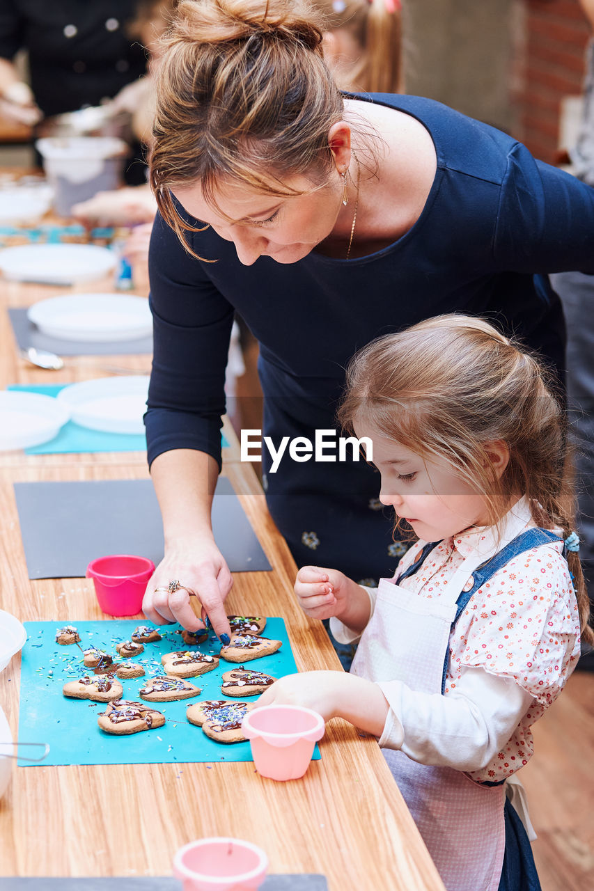 MOTHER AND DAUGHTER ON TABLE WITH HANDS