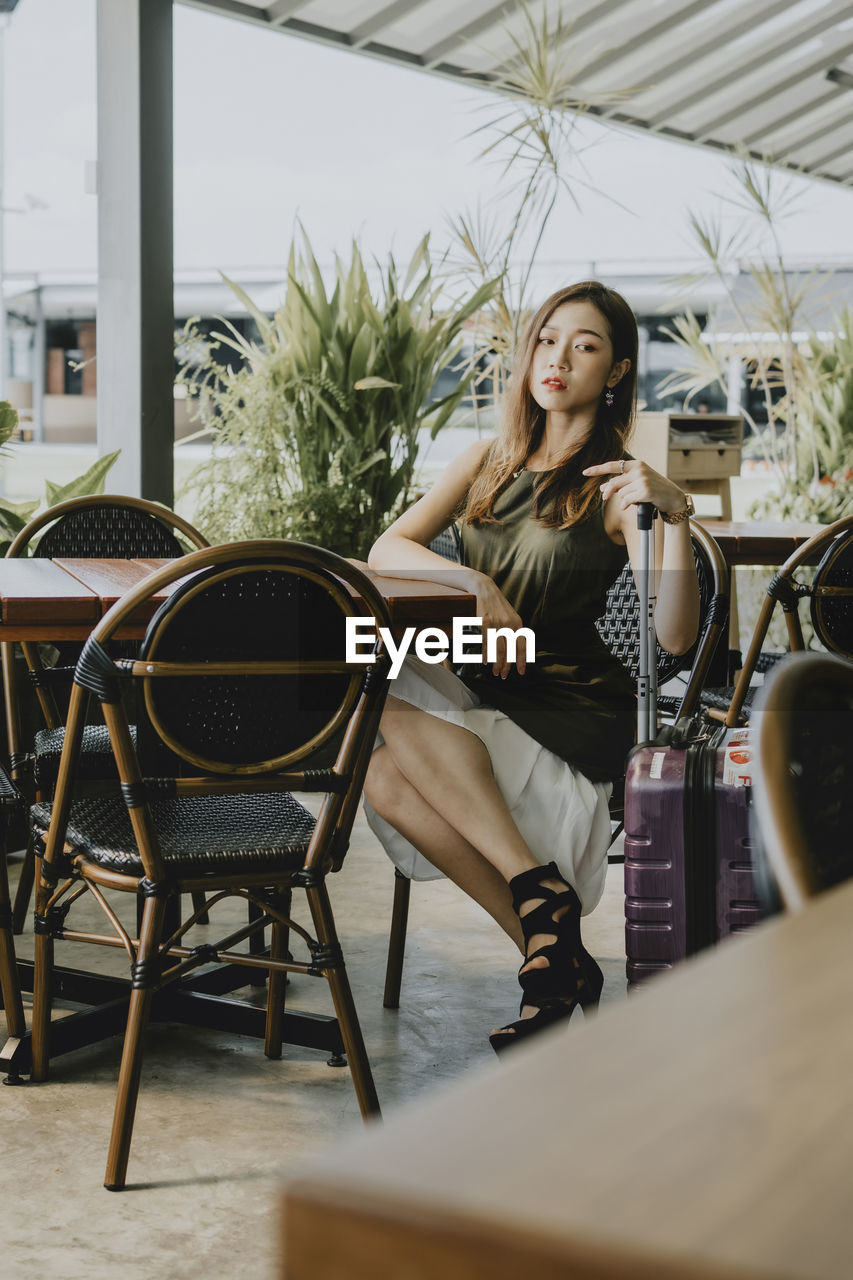 Young woman with luggage sitting in cafe