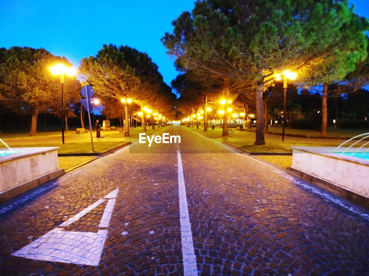 ILLUMINATED STREET LIGHTS ON ROAD AT NIGHT