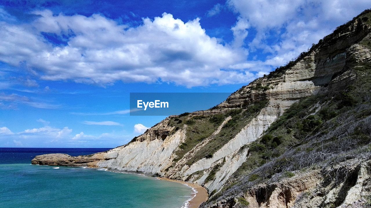 Scenic view of rocky mountains by sea against sky