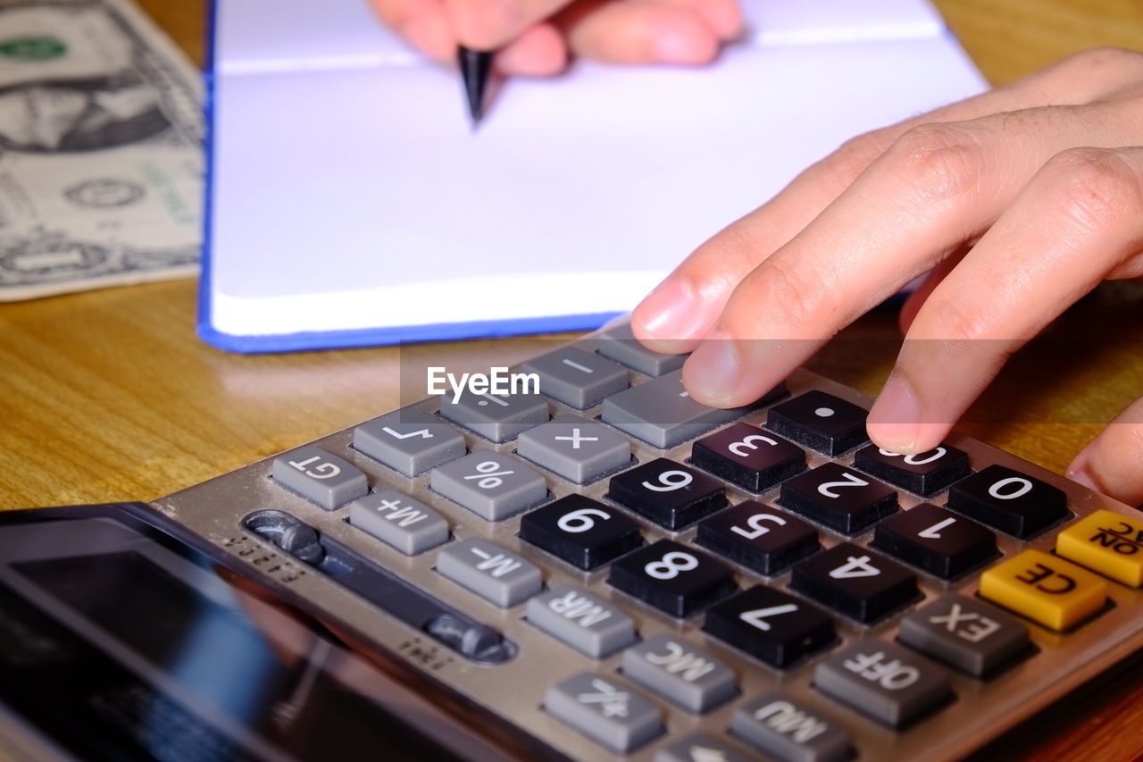 Cropped hands of man calculating on table