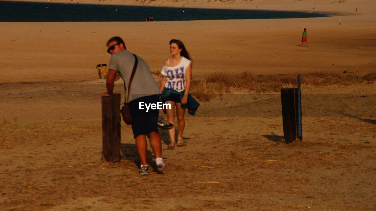FULL LENGTH OF YOUNG WOMAN STANDING ON RAILING