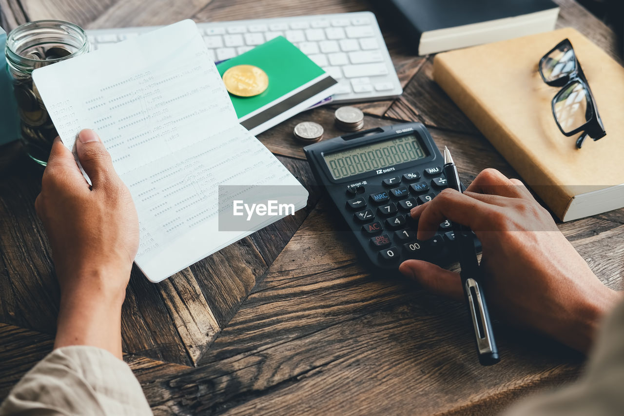 Midsection of businessman using calculator on table 