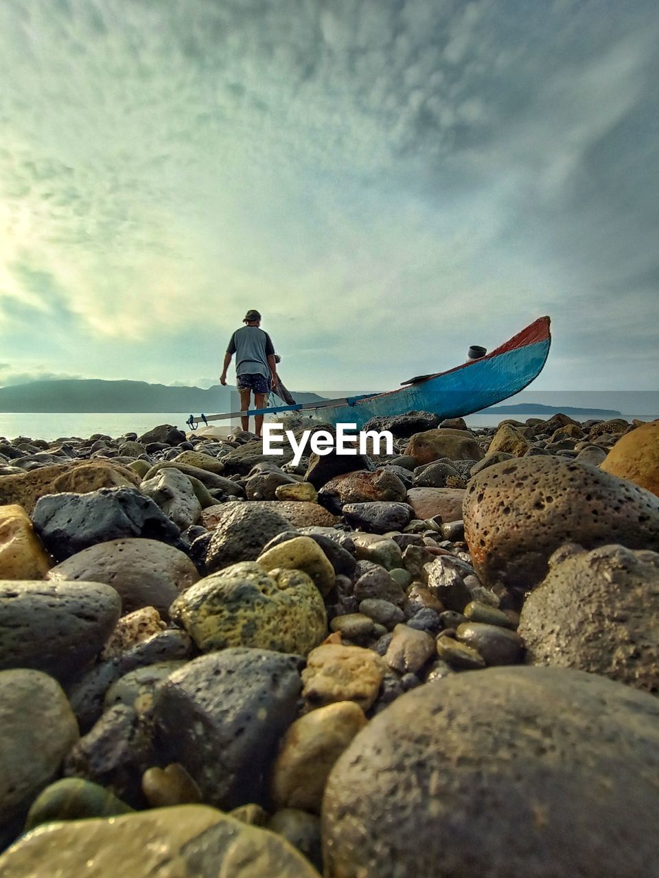 People standing on rocks by sea against sky