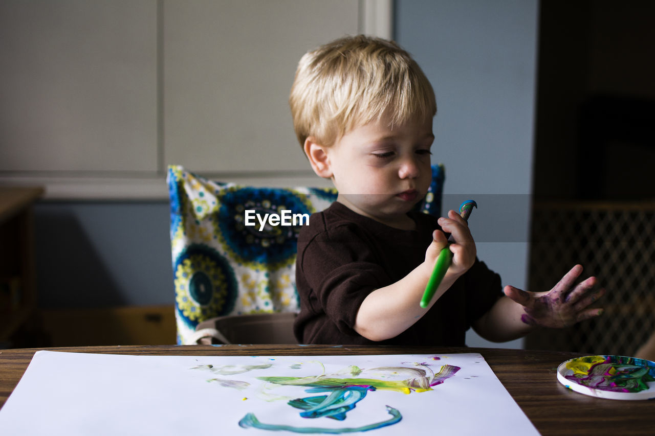 Cute boy drawing on paper while sitting at home