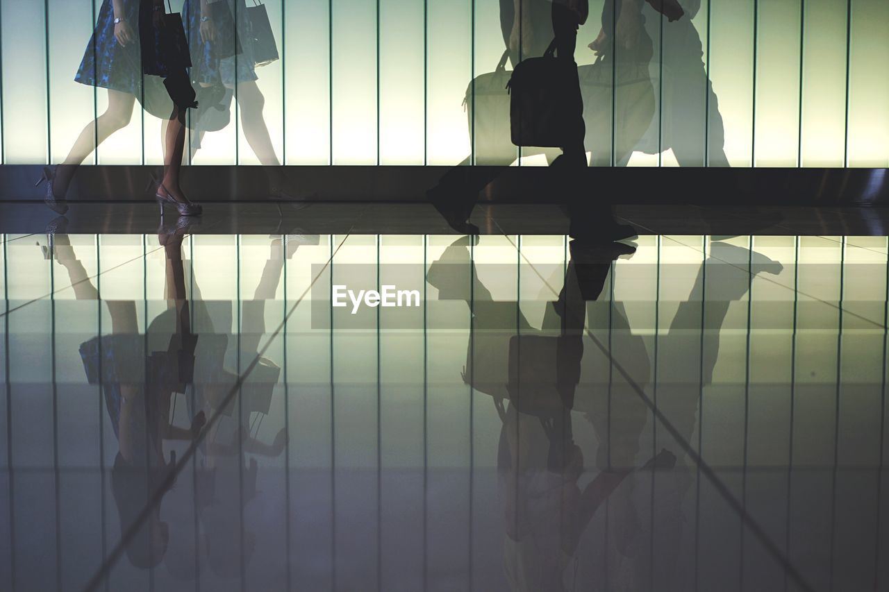 Low section of people walking on tiled floor in building