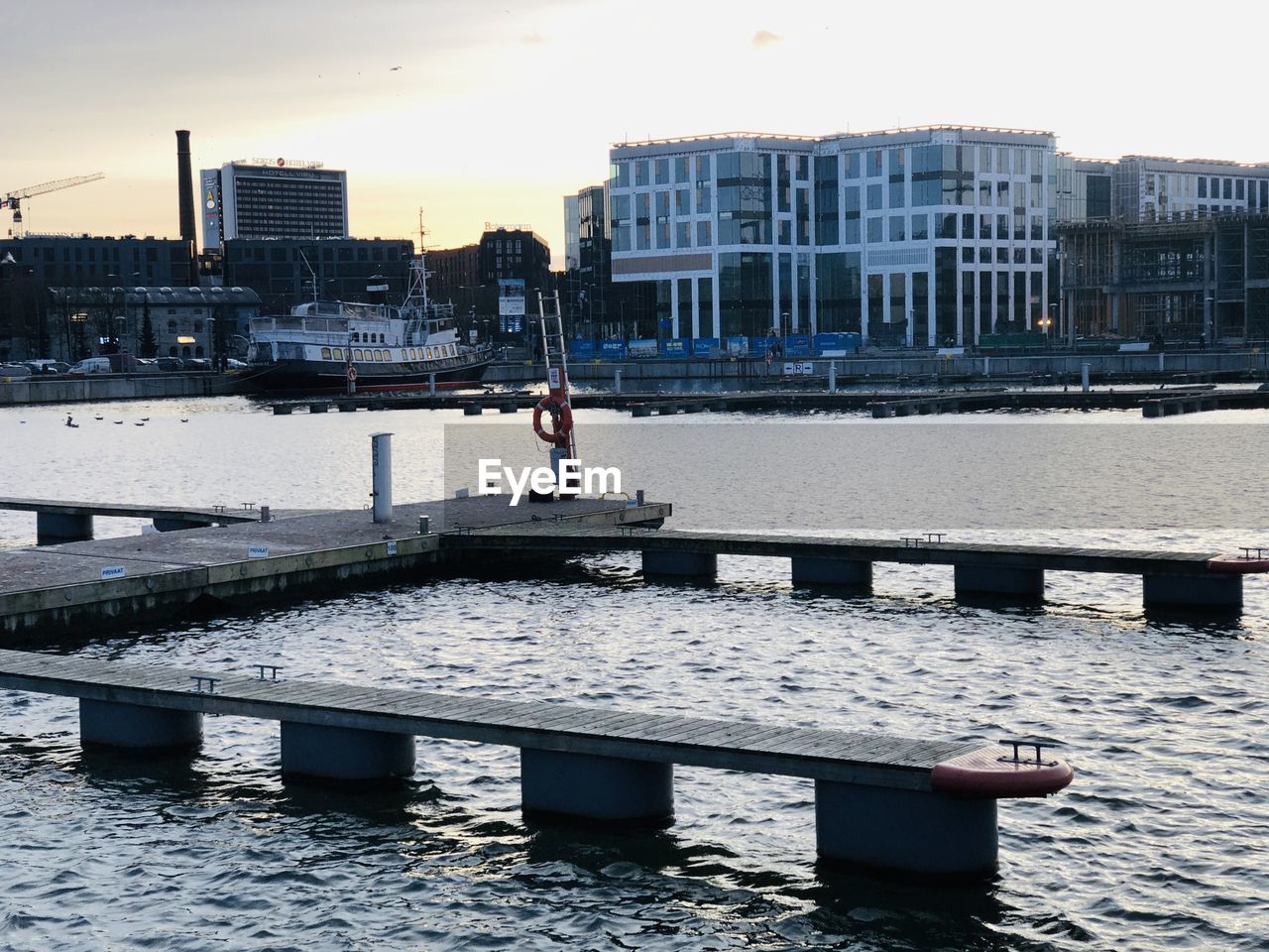 PERSON ON RIVER BY BUILDINGS IN CITY AGAINST SKY