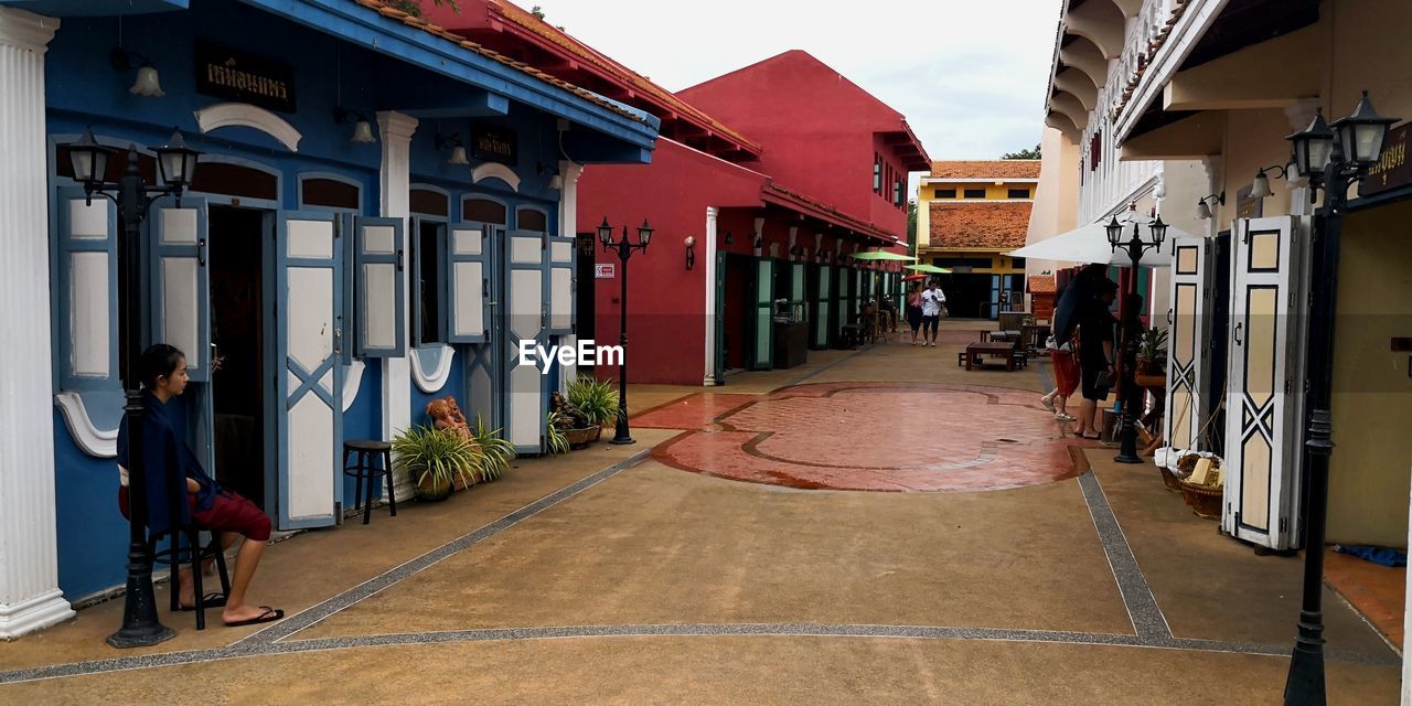 PEOPLE ON STREET AMIDST HOUSES IN CITY