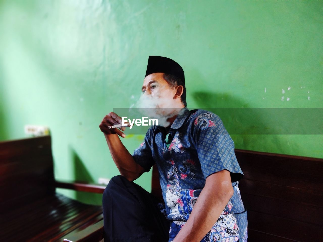 MAN SMOKING CIGARETTE WHILE SITTING ON TABLE