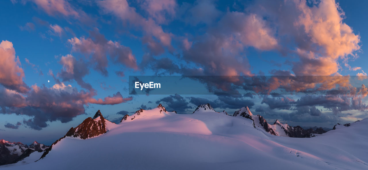Panoramic view of snow covered mountains against sky