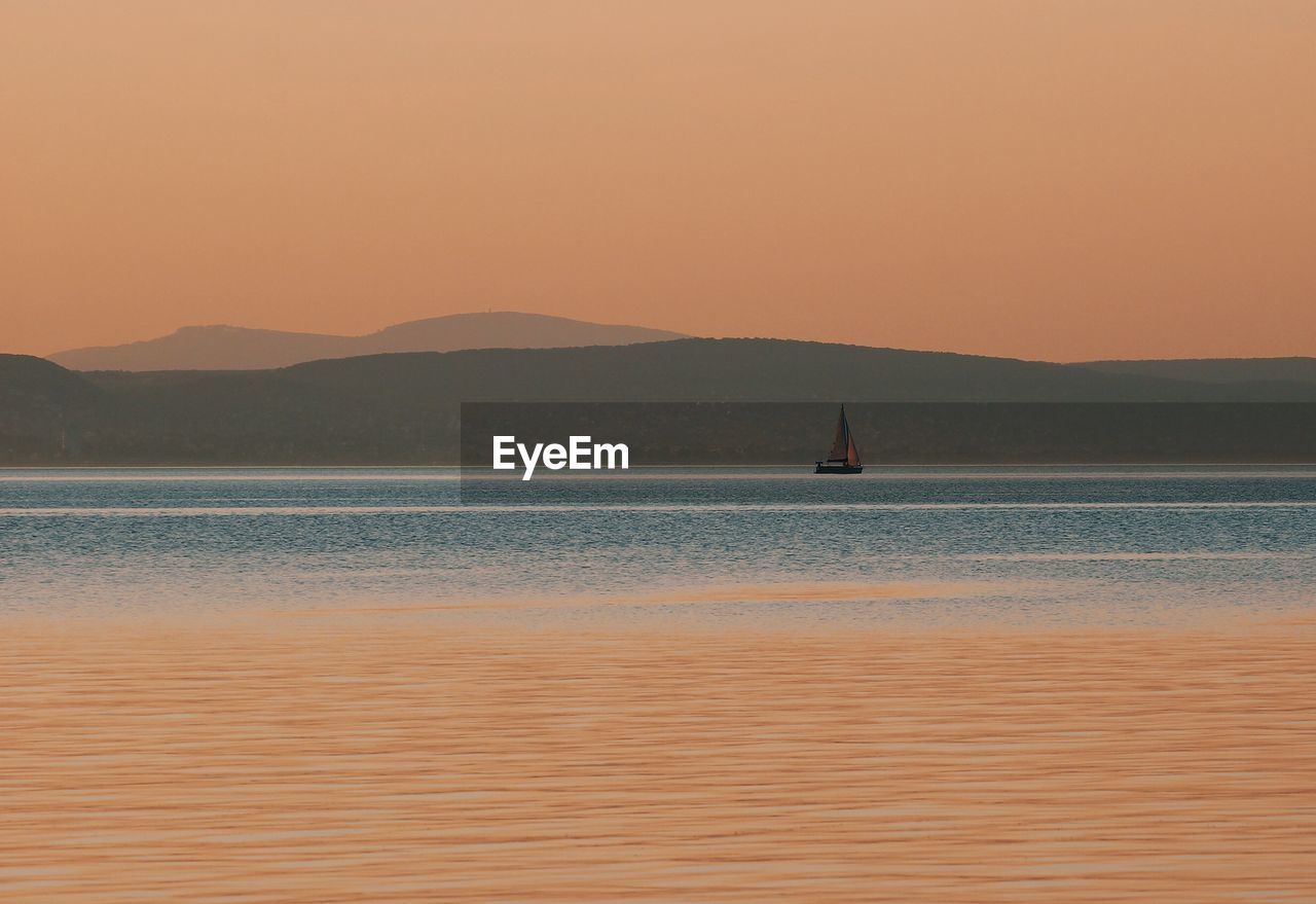 Silhouette of boat sailing in sea at sunset