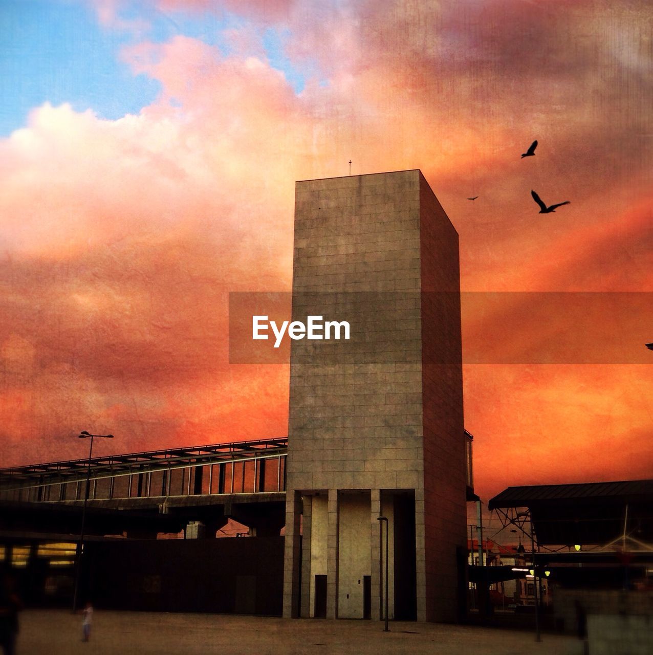 VIEW OF BUILDINGS AGAINST CLOUDY SKY AT SUNSET