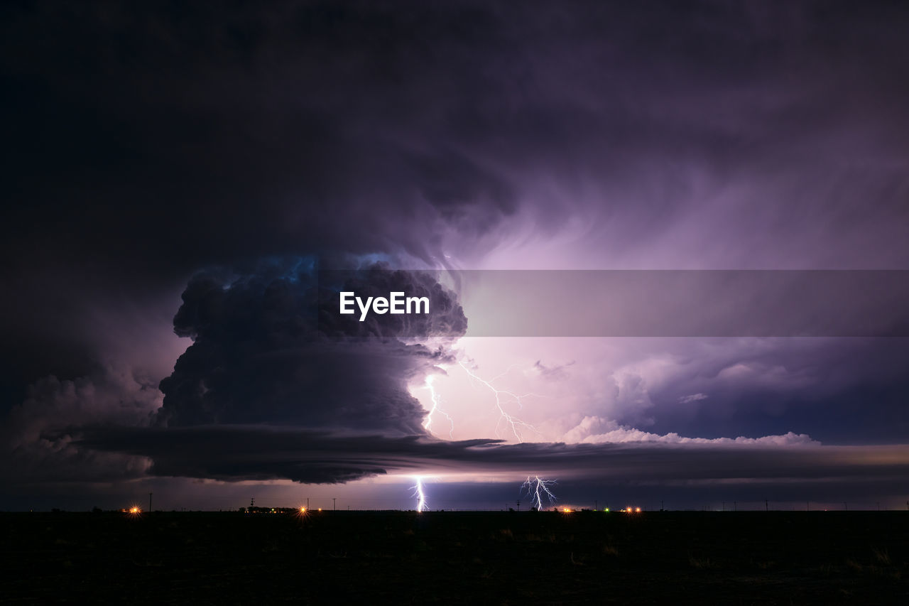 Lightning bolts illuminate a supercell thunderstorm in the night sky near earth, texas.