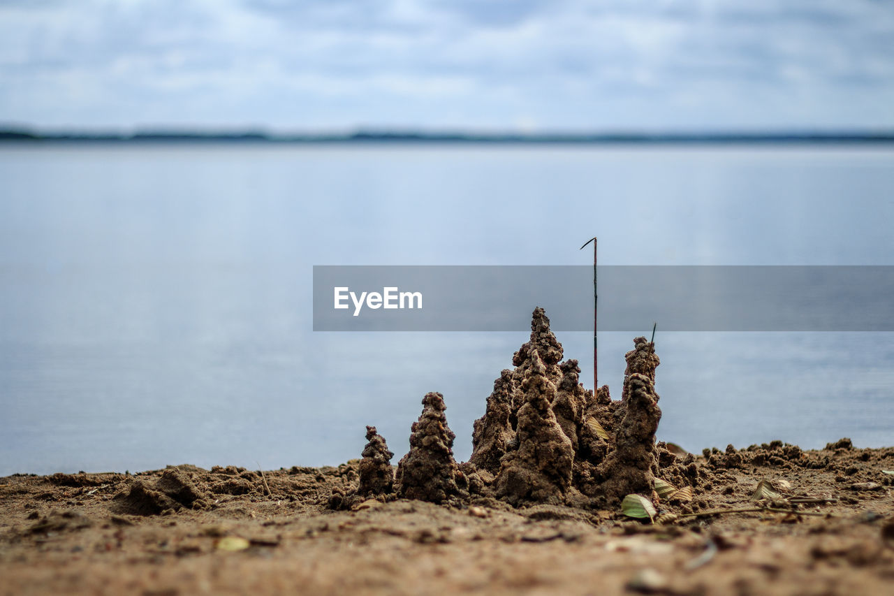 Close-up of sand castle by lake against sky