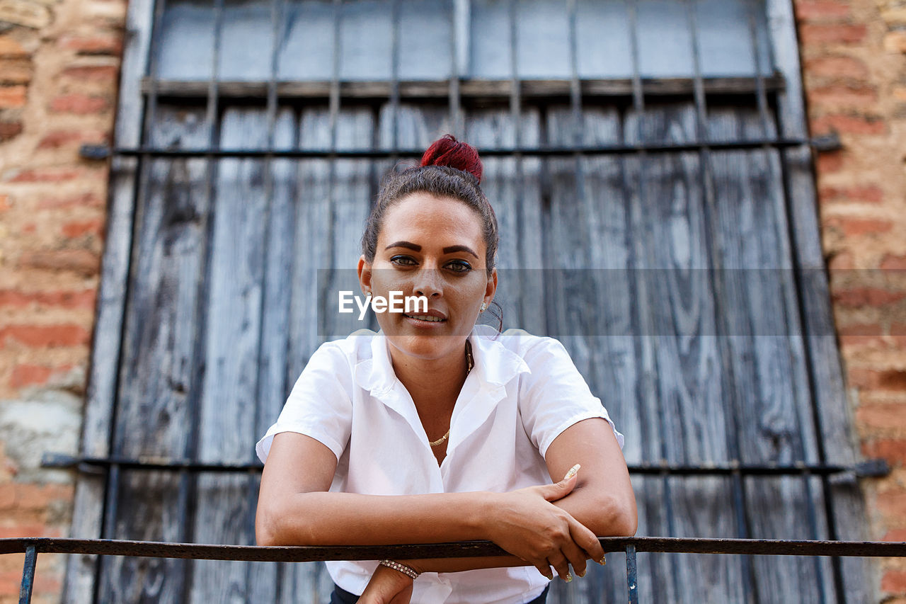 Portrait of young woman leaning on railing