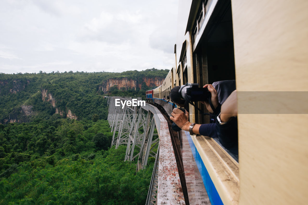 Cropped image of person photographing mountains from train