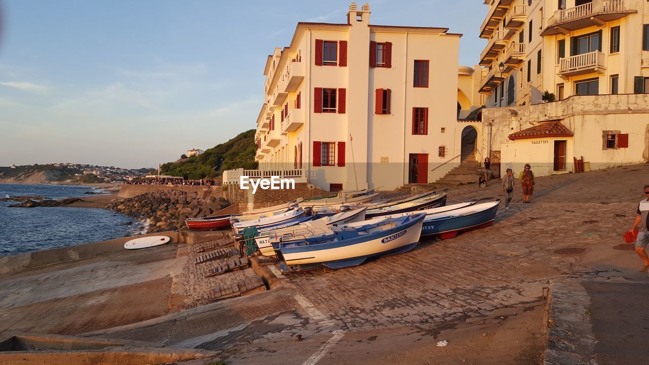 BOATS MOORED ON SEA BY BUILDINGS AGAINST SKY