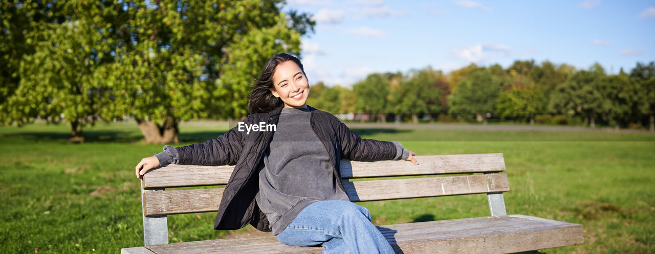 portrait of young woman sitting on bench at park