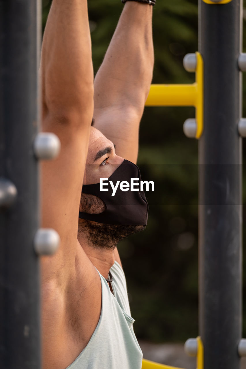 Close-up of young man wearing flu mask exercising outdoors